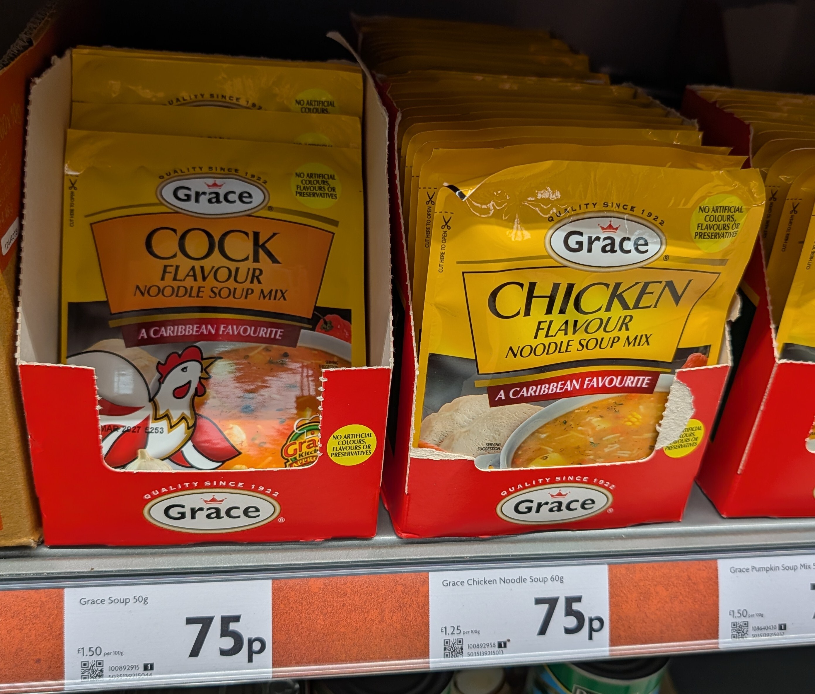 Photo of a supermarket shelf with packets of "Cock Flavour Soup" mix, next to "Chicken Flavour Soup" mix, by the same brand.