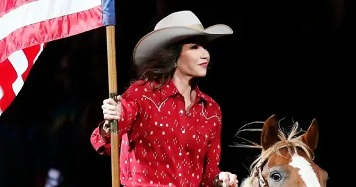 Kristi Noem riding a horse carrying a flag