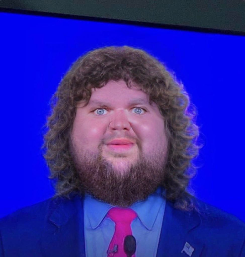JD Vance photoshopped to be very chubby and have curly hair and a shaggy neckbeard.