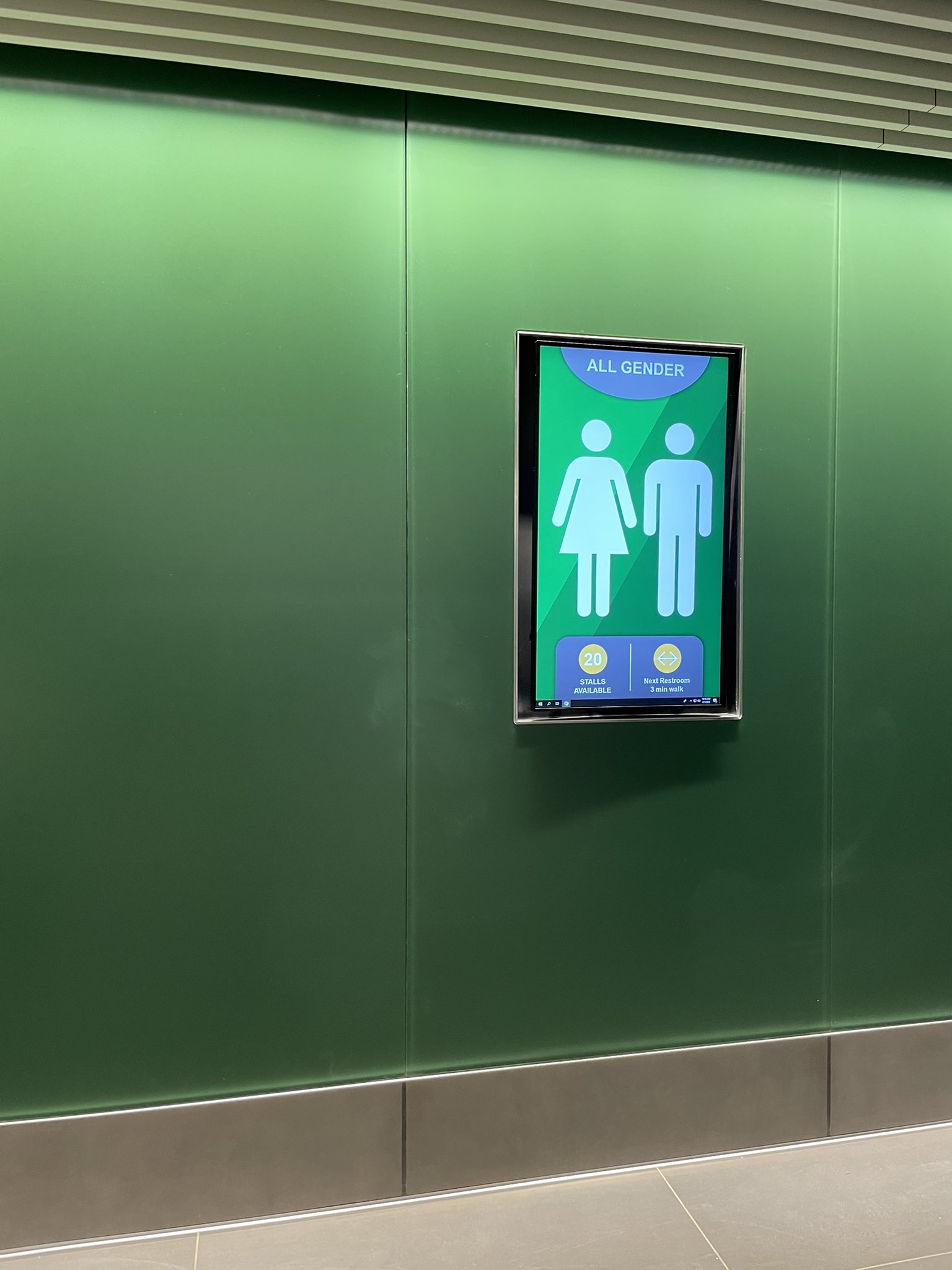 Image taken from a transphobe on twitter showing a monitor that says "All Gender, 20 Stalls Available, Next restroom 3 minute walk"