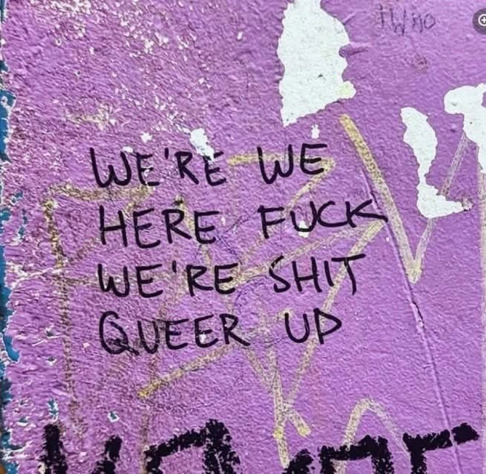Graffiti that, read from left to right top to bottom, says, “we’re we here fuck we’re shit queer up”