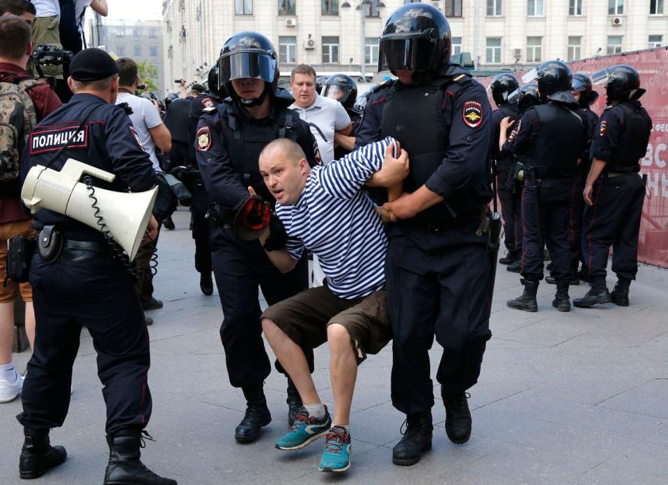 Man in striped shirt detained at a protest