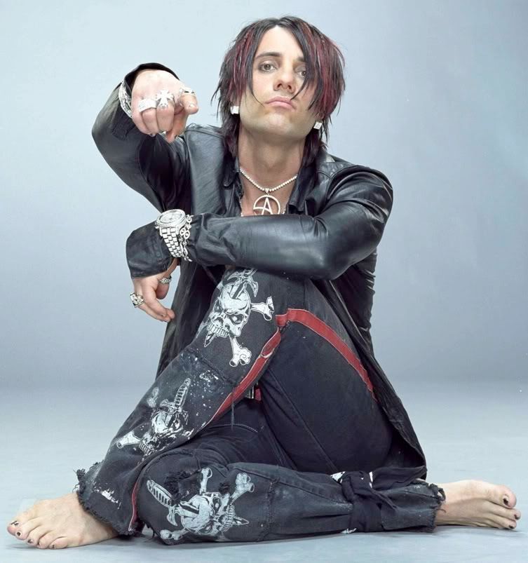 Illusionist Criss Angel, dressed in his best early-2000s over-the-top emo clothes and jewelry, stares and points dramatically at the viewer while curled up in a particularly gothy pose as if to say "Mind freak!"