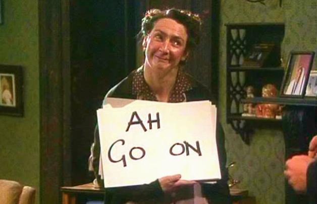 Mrs. Doyle (from Father Ted) with placard reading "Ah, Go On" 