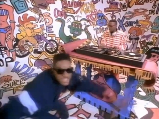 Screenshot of DJ Jazzy Jeff and the Fresh Prince in front of the hip-hop background which was their visual signature at the time, bright white walls and floors with colorful but family-friendly 1990s graffiti spray-painted all over every surface