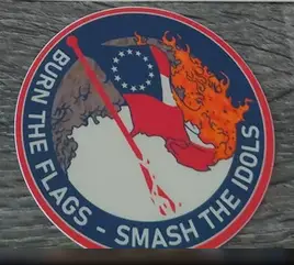 Photo of a detail of OP's photo, representing a sticker with a burning Betsy Ross flag surrounded by the text "Burn the flags - Smash the idols"