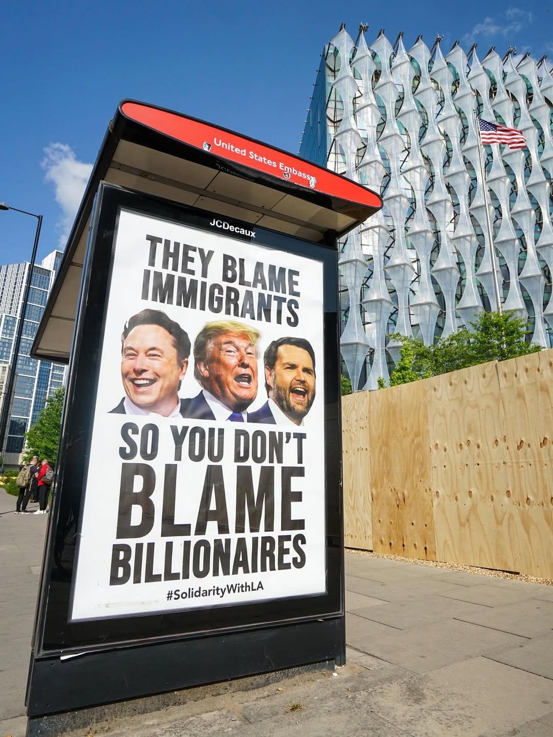 people vs Elon campaign ad at US embassy bus stop in London. Musk, Trump and Vance. caption they blame immigrants so you don't blame billionaires